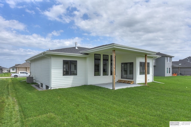 rear view of house with central AC unit, a lawn, and a patio