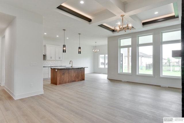 kitchen featuring white cabinetry, light wood-type flooring, a kitchen island with sink, and plenty of natural light