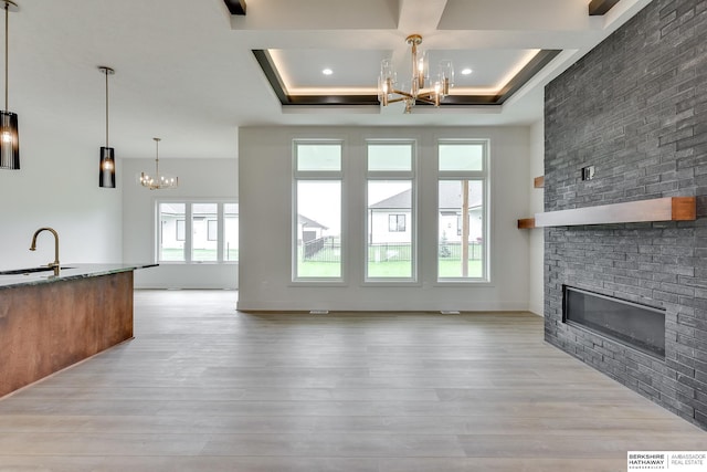 unfurnished living room with a brick fireplace, light hardwood / wood-style flooring, and a tray ceiling