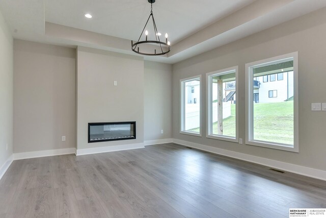 unfurnished living room with an inviting chandelier, plenty of natural light, and light hardwood / wood-style flooring