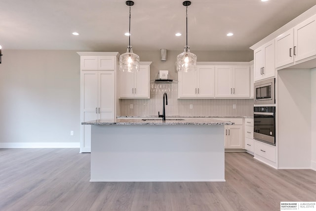 kitchen with decorative light fixtures, white cabinetry, appliances with stainless steel finishes, and sink