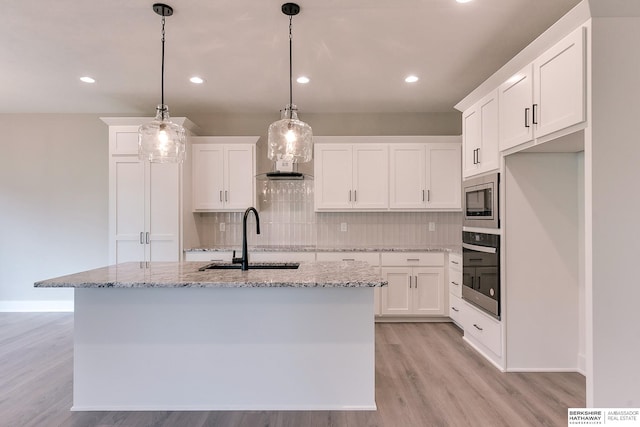 kitchen with a kitchen island with sink, appliances with stainless steel finishes, sink, and white cabinets