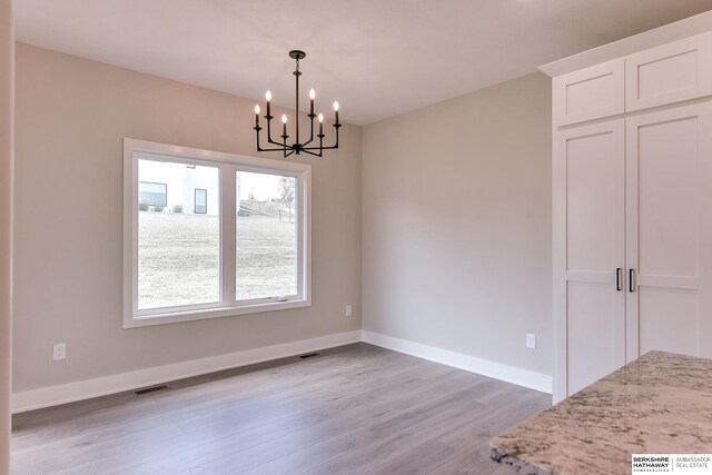 unfurnished dining area with a notable chandelier and light hardwood / wood-style floors