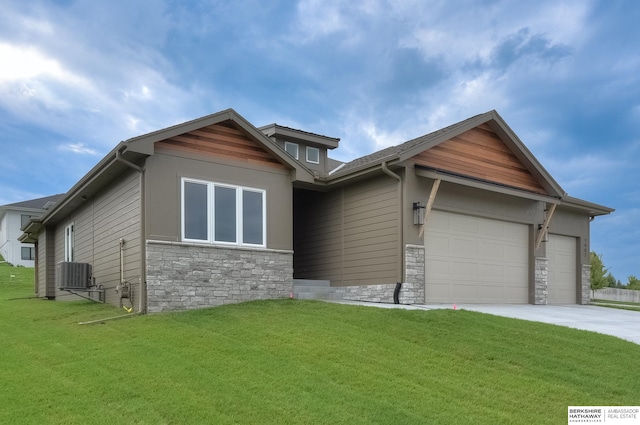 view of front of home with a garage, central AC unit, and a front lawn