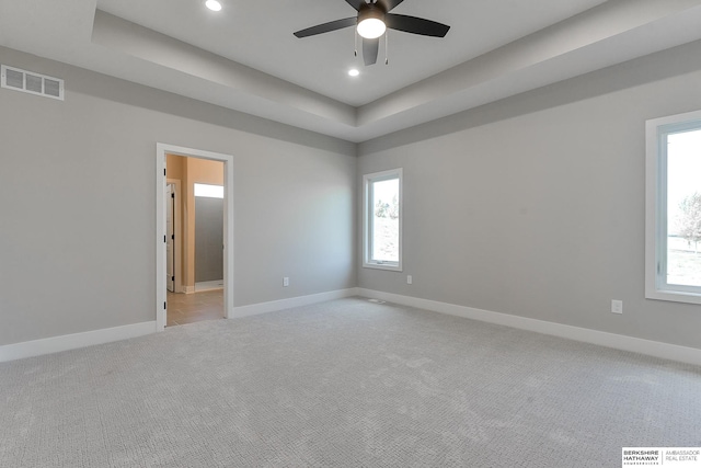 spare room with light colored carpet, ceiling fan, and a tray ceiling