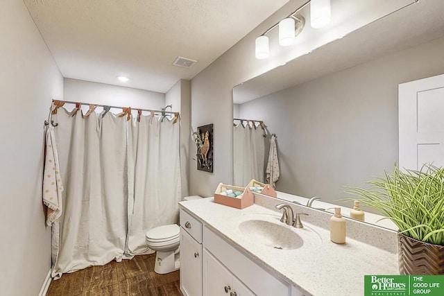 bathroom with wood-type flooring, a textured ceiling, toilet, and vanity