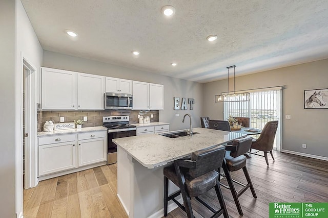 kitchen featuring stainless steel appliances, white cabinetry, and light wood-type flooring