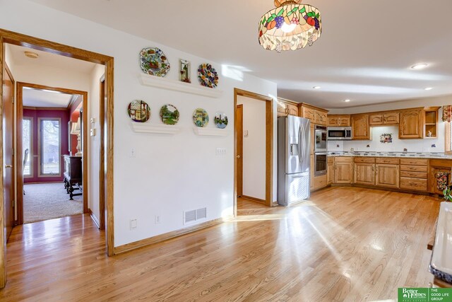 kitchen with pendant lighting, light wood-type flooring, and appliances with stainless steel finishes