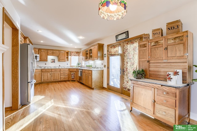 kitchen featuring light hardwood / wood-style floors, light stone countertops, and appliances with stainless steel finishes