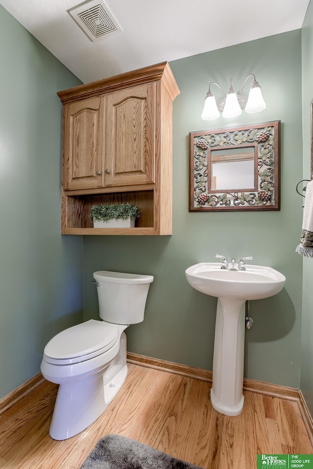 bathroom featuring wood-type flooring, toilet, and sink