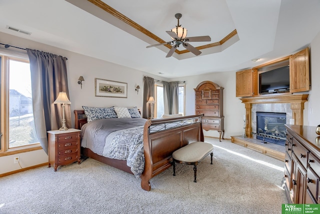 carpeted bedroom featuring ornamental molding, a raised ceiling, ceiling fan, and a fireplace