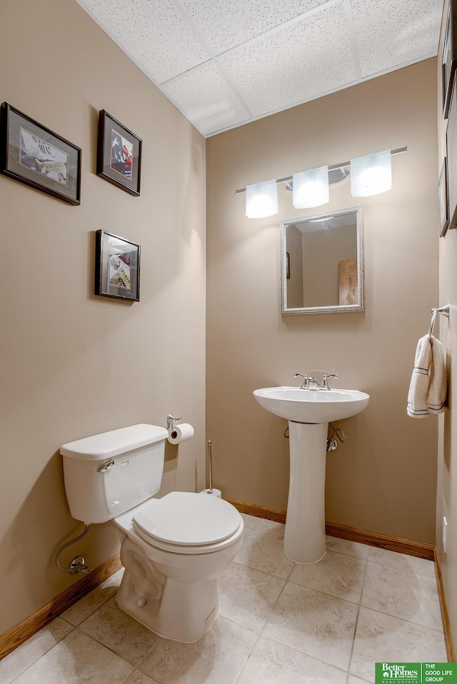 bathroom featuring tile patterned flooring, toilet, and a paneled ceiling