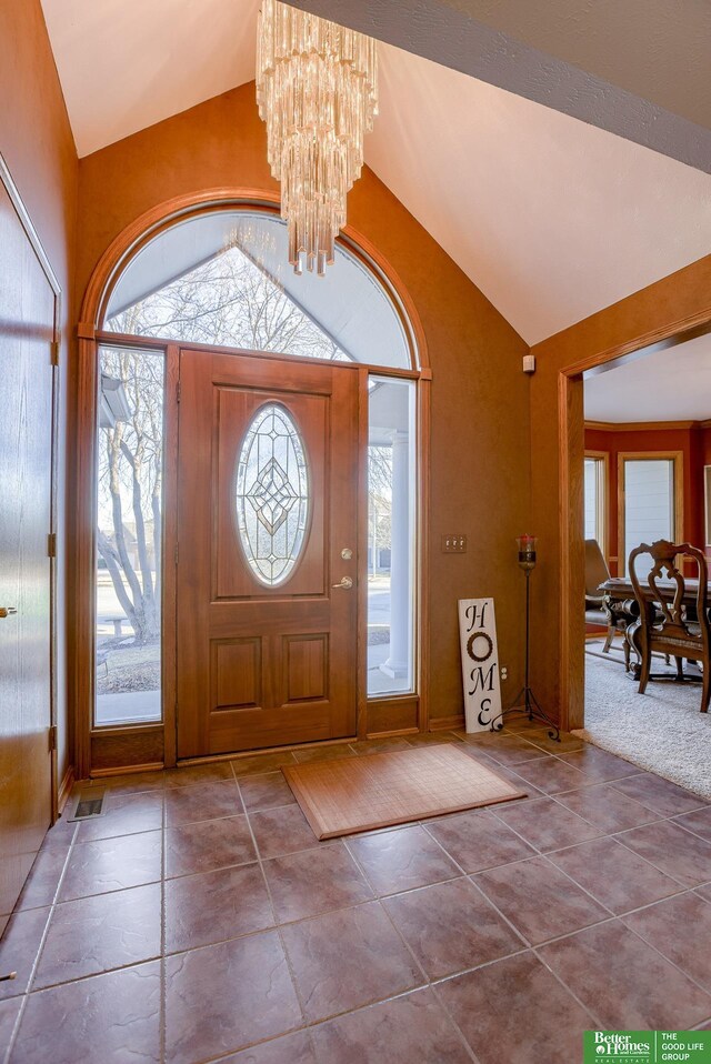 tiled foyer with plenty of natural light, lofted ceiling, and a chandelier