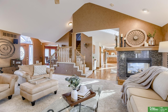 living room with a premium fireplace, light wood-type flooring, and high vaulted ceiling