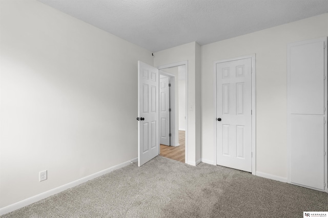 unfurnished bedroom featuring light colored carpet, a textured ceiling, and a closet