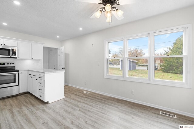 kitchen featuring stainless steel appliances, white cabinets, plenty of natural light, and light wood-type flooring