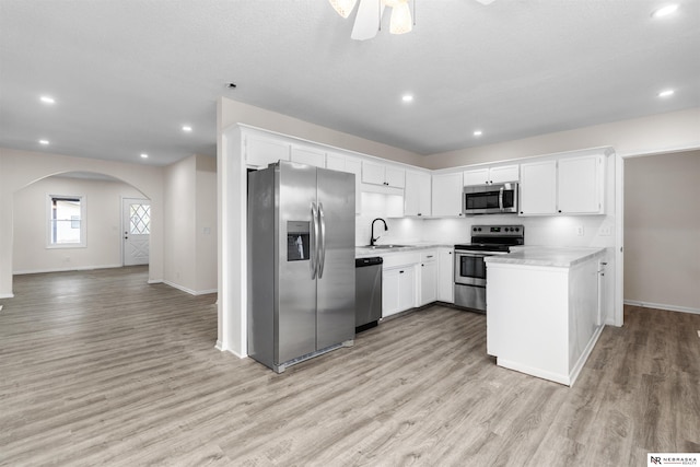 kitchen featuring stainless steel appliances, light hardwood / wood-style floors, sink, ceiling fan, and white cabinetry