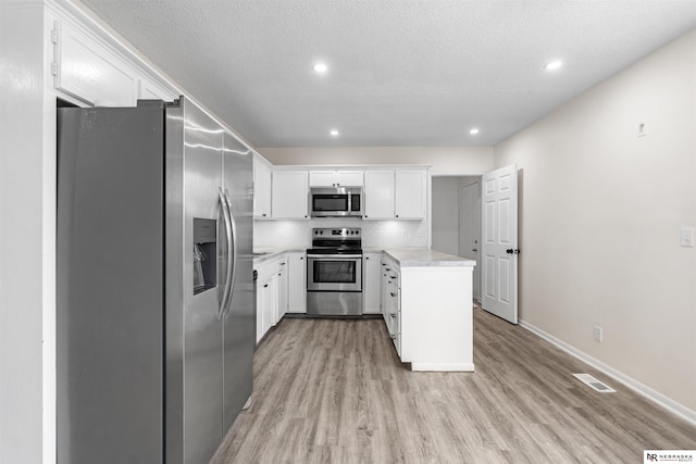 kitchen featuring light hardwood / wood-style floors, white cabinets, a textured ceiling, backsplash, and appliances with stainless steel finishes