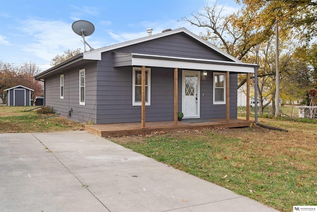 bungalow-style home with a porch, a front lawn, and a shed