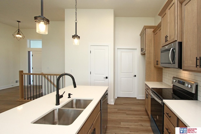 kitchen featuring stainless steel appliances, dark wood-type flooring, sink, tasteful backsplash, and decorative light fixtures