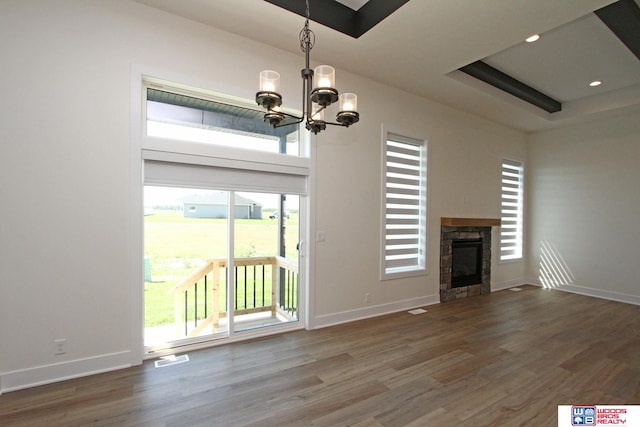 unfurnished living room with a fireplace, wood-type flooring, a healthy amount of sunlight, and an inviting chandelier