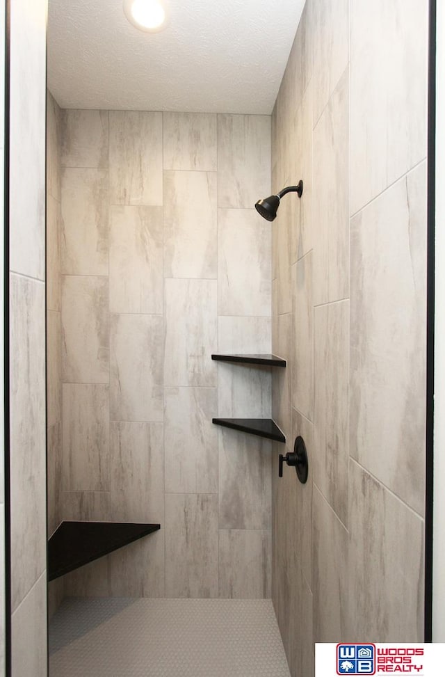 bathroom with a textured ceiling and a tile shower