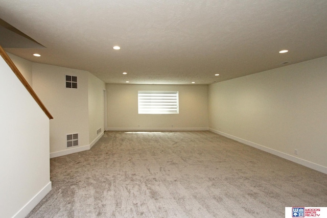 basement featuring a textured ceiling and light carpet