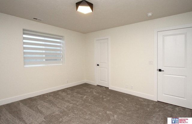 spare room with dark colored carpet