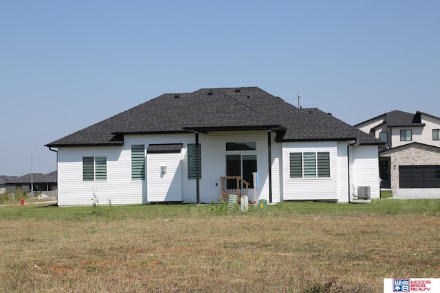 rear view of house with a garage, cooling unit, and a yard