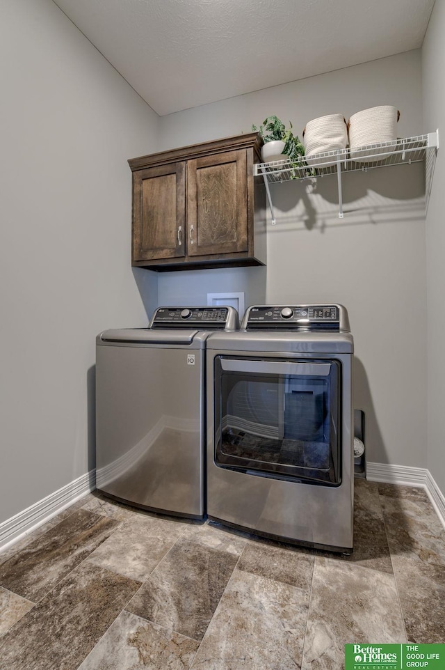 washroom with cabinets, washer and dryer, and a textured ceiling