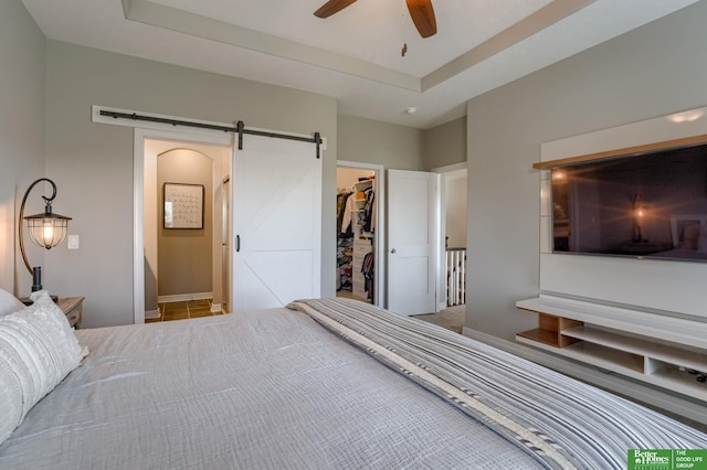 bedroom featuring ensuite bath, ceiling fan, a walk in closet, a barn door, and a closet