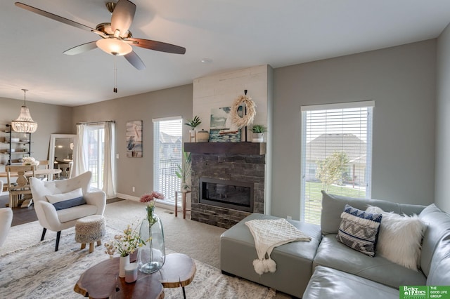 living room with a stone fireplace, light colored carpet, and ceiling fan