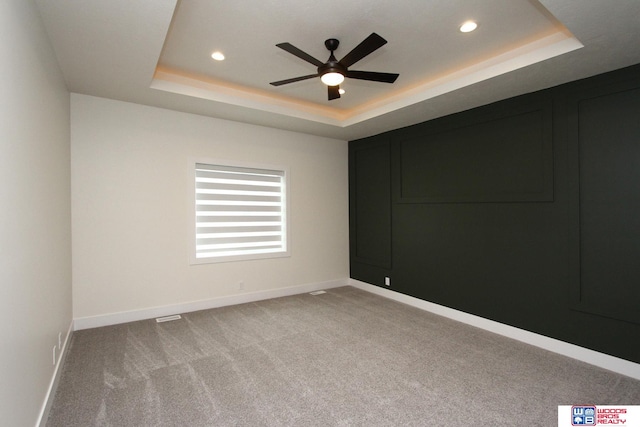 unfurnished room featuring light carpet, ceiling fan, and a tray ceiling