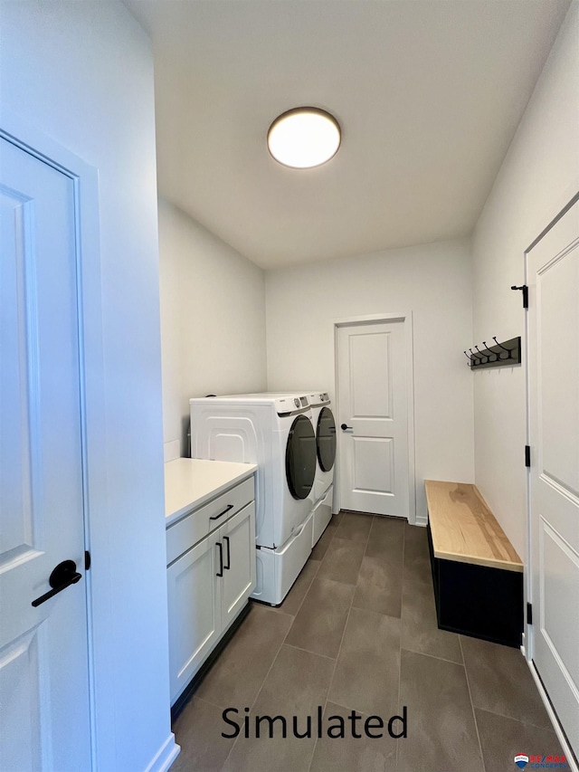 laundry area featuring cabinets, dark tile patterned flooring, and washing machine and clothes dryer