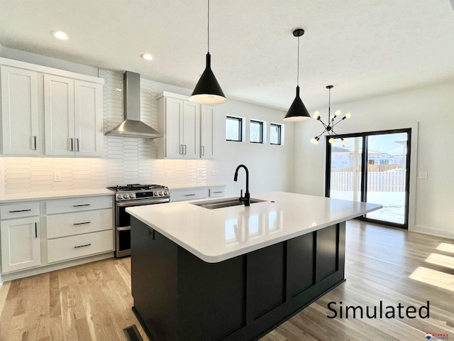 kitchen with white cabinets, wall chimney exhaust hood, sink, double oven range, and a center island with sink