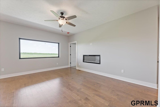 216 St Andrews Loop, Malvern, IA 51551 - empty room featuring ceiling fan, wood finished floors, baseboards, and a glass covered fireplace