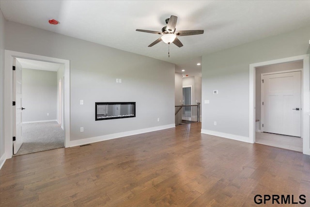 216 St Andrews Loop, Malvern, IA 51551 - unfurnished living room with ceiling fan, wood finished floors, a glass covered fireplace, baseboards, and recessed lighting