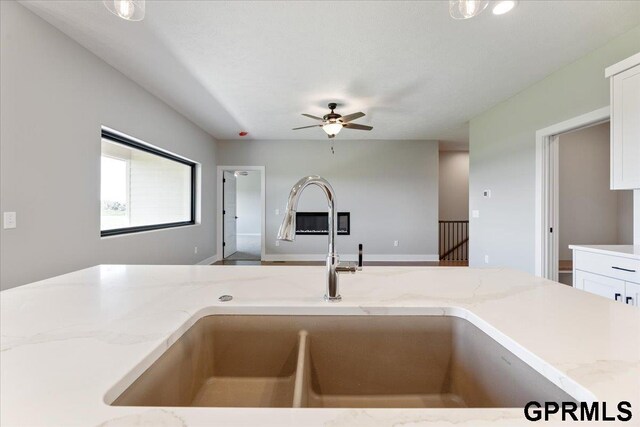 216 St Andrews Loop, Malvern, IA 51551 - kitchen with a sink, ceiling fan, light stone counters, and white cabinetry