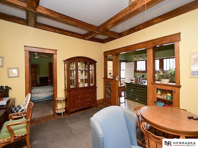 interior space with ornate columns, beam ceiling, coffered ceiling, dark colored carpet, and ceiling fan