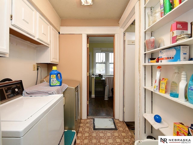 clothes washing area featuring a textured ceiling, light wood-type flooring, washing machine and dryer, and cabinets