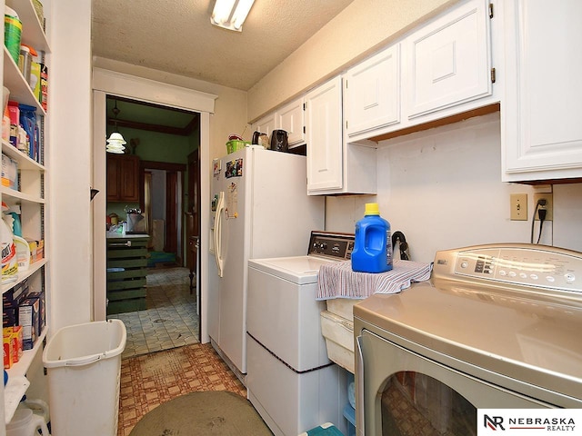 laundry room with cabinets, washing machine and clothes dryer, and a textured ceiling