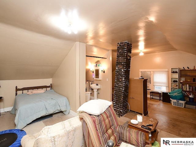 bedroom featuring lofted ceiling, hardwood / wood-style floors, and ensuite bath