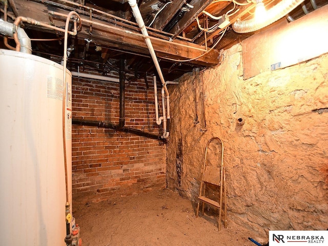 basement featuring gas water heater and brick wall