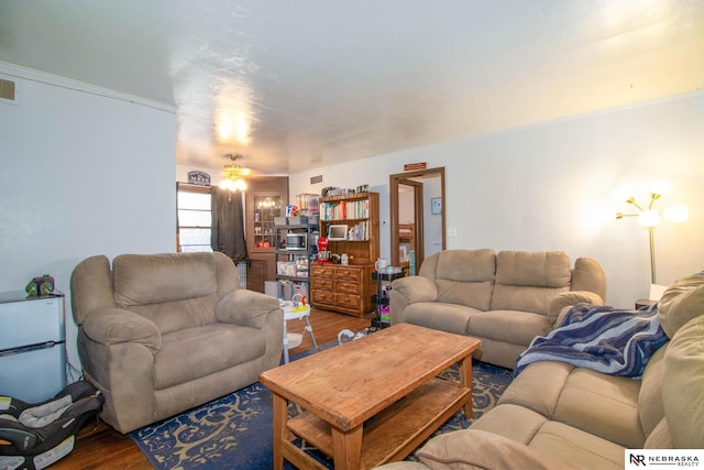 living room featuring wood-type flooring, ceiling fan, and crown molding