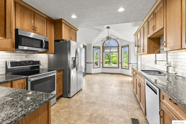 2119 N 144th Ave, Omaha, NE 68116 - kitchen featuring appliances with stainless steel finishes, a sink, vaulted ceiling, brown cabinets, and tasteful backsplash