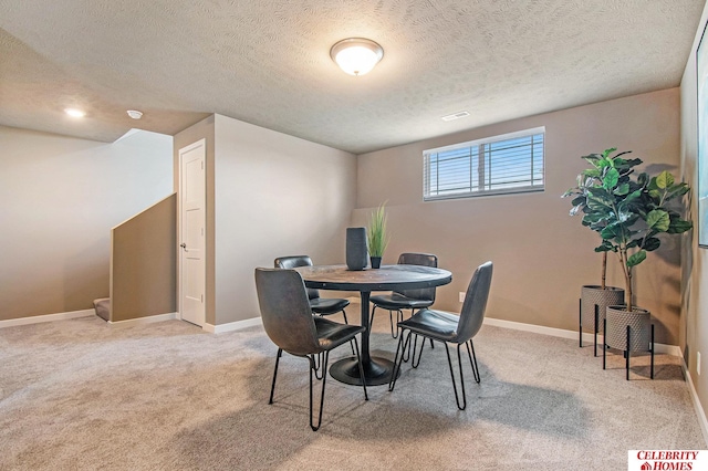 carpeted dining area featuring a textured ceiling