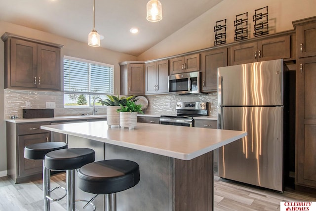 kitchen featuring tasteful backsplash, appliances with stainless steel finishes, lofted ceiling, and hanging light fixtures