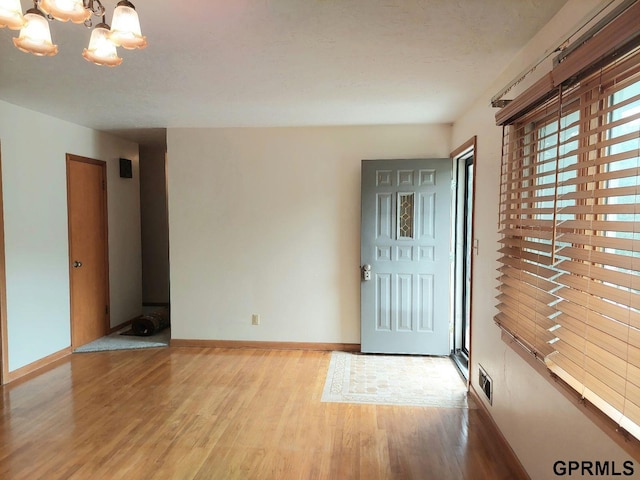 foyer entrance with light hardwood / wood-style floors and a chandelier