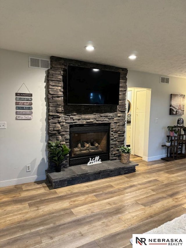 living room featuring a stone fireplace and hardwood / wood-style flooring