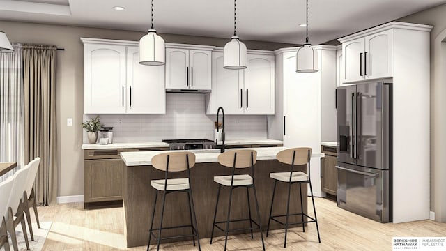 kitchen featuring light hardwood / wood-style floors, a center island with sink, hanging light fixtures, tasteful backsplash, and stainless steel fridge